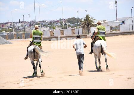 Sale, Marokko. Juni 2020. Am Strand patrouillieren berittene Soldaten, die einen Mann dazu bringen, am 14. Juni 2020 in Sale, Marokko, zu gehen. Marokko hat am Sonntag 101 neue COVID-19-Infektionen angekündigt, was die Gesamtzahl der bestätigten Fälle im nordafrikanischen Land auf 8,793 erhöht. Quelle: Chadi/Xinhua/Alamy Live News Stockfoto