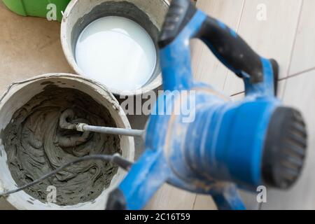 Ein voller Eimer mit speziellem Fliesenkleber, fertig zum Gebrauch. Klebstoffmischer auf Zementbasis. Stockfoto