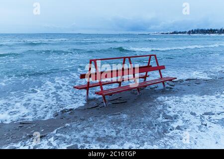 Rote Bank von Eis bedeckt wird von Wintermeer getroffen. Eisige Wellen der Ostsee am leeren Strand. Stockfoto