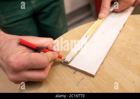 Der Bauherr misst den Abstand auf der Keramikplatte mit einem Maßband. Abstandsmessung während der Bearbeitung des Fliesenlader. Stockfoto