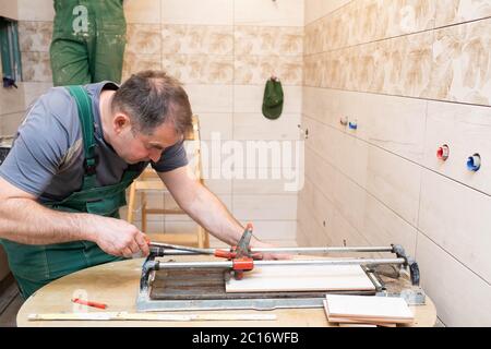 Fliesenschneidemaschine. Bauarbeiter. Präzises Schneiden von Keramikfliesen. Stockfoto