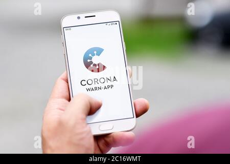 Offizielle deutsche Corona Warnung App auf Handy von Hand gehalten auf verschwommenem Hintergrund Stockfoto