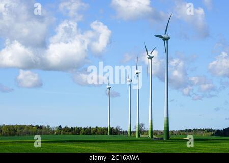 Fünf Windturbinen Masten in einem grünen Feld auf einem blauen Himmel Hintergrund Stockfoto