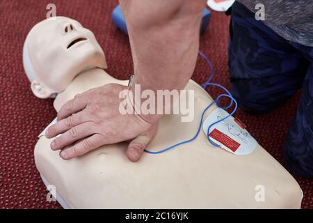 Männlicher Instruktor, der kardiopulmonale Reanimation mit HLW-Dummy unterrichtet Stockfoto