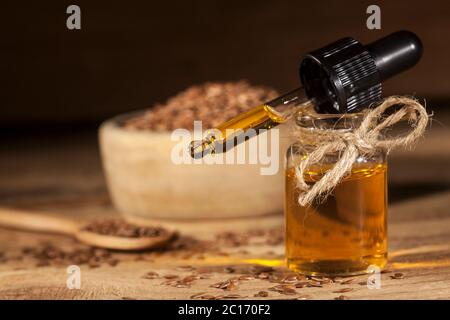 Leinöl, Löffel und Schale Leinsamen auf Holzgrund Stockfoto