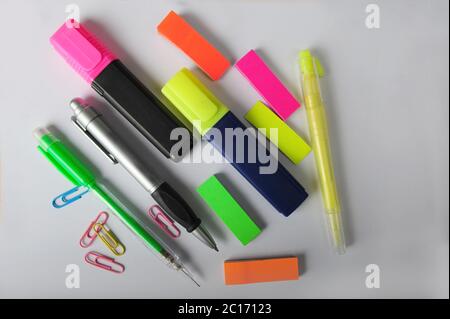 Bunte Marker, Stifte, Büroklammern und Post-it-Tabs, die von oben auf einem Stück weißem Papier aufgenommen wurden. Stockfoto