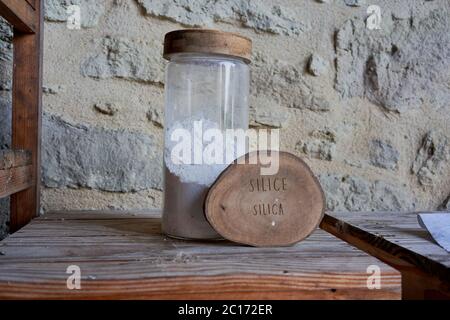 Glas mit Silicastaub neben einer hölzernen Scheibe mit der Aufschrift Silice Silica auf einem rustikalen Regal, verwendet in der biodynamischen Weinbergarbeit im Chateau de La Dauphine, Fronsac Stockfoto