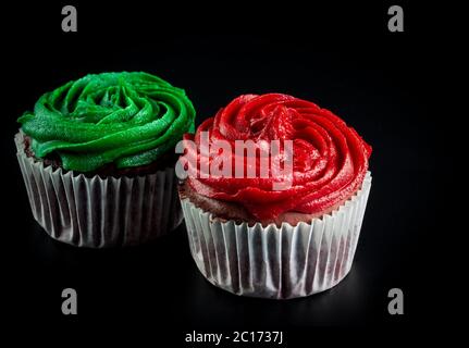 Zwei Muffins, rot und grün auf schwarzem Hintergrund isoliert Stockfoto