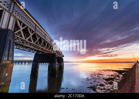 Sonnenuntergang und die Tay Rail Bridge, als ein Zug vorbeifährt, Dundee, Schottland, Vereinigtes Königreich. Stockfoto