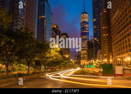 NYC bei Sonnenaufgang mit Autolichtern im Vordergrund und Gebäuden im Hintergrund Stockfoto