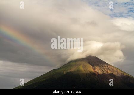 Ein Regenbogen berührt den Conception Vulkan an einem bewölkten Tag auf der Insel Ometepe, Nicaragua. Stockfoto