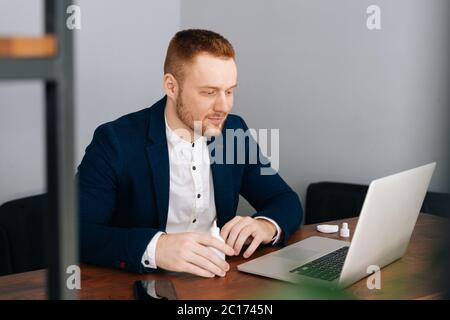 Serious jungen Geschäftsmann tragen Mode Anzug ist die Anwendung Desinfektionsmittel Stockfoto