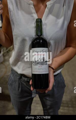 Führer in einer weißen Bluse hält eine Flasche Château du Tailhas Pomerol Rotwein, Bordeaux, Frankreich Stockfoto