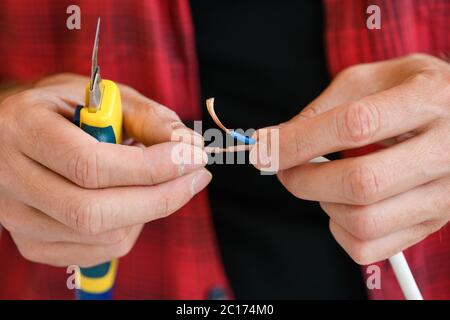 Männliche Hände mit Messer und elektrischen Kabeln Stockfoto