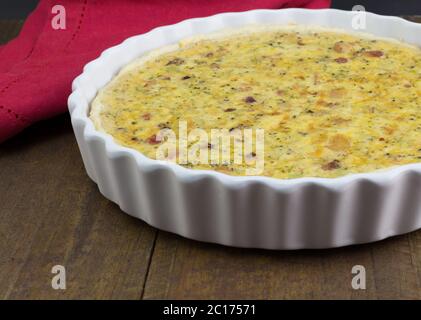 Quiche mit Käse, Speck und Pilzen auf rustikalem Holztisch - Offene Torte in weißer Schale mit selectiv Stockfoto