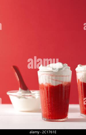 Erdbeer Smoothie Shakes im Glas mit Schlagsahne auf rotem Hintergrund mit Copy Space.Summer erfrischenden Drink Mocktail Stockfoto