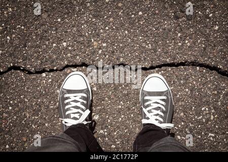 Mann steht auf gesprungenem Asphaltboden Stockfoto