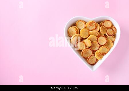 Winzige Pfannkuchen zum Frühstück in weißem Schüssel-förmigen Herz auf rosa Hintergrund, trendige Lebensmittel, Copy Space für Text oder Design Stockfoto