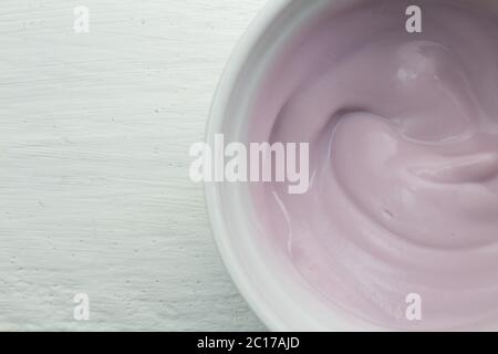 Cremig natürlich gefärbte Himbeer-Frucht-Joghurt in weißen Glasschüssel auf weißem Holztisch close up top Stockfoto