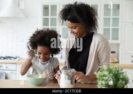 Kleine Tochter und afrikanische Mutter kochen zusammen in der Küche Stockfoto