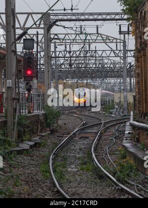 Virgin Trains der Baureihe 390 Alstom pendolino mit rotem Signal an der Hauptlinie der Westküste in Crewe Stockfoto