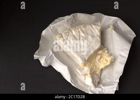 Brie Art von Käse. Camembert Käse. Frischer Brie-Käse-Keil auf schwarzem Hintergrund mit Text Spa geschnitten Stockfoto