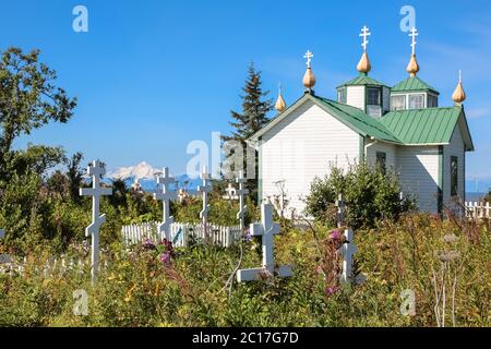 Russische orthodoxe Kirche die Verklärung unseres Herrn und Friedhof, Ninilchik, mit Vulkan in der Stockfoto