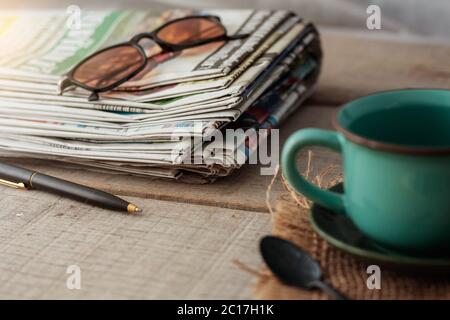 Zeitungen und Tassen auf Holz. Stockfoto