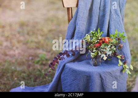 Blumenkomposition auf dem Stuhl mit Textilstruktur verziert Stockfoto