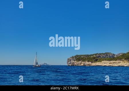 Ein Segelboot, das entlang der spektakulären Küste des Parc national des Calanques (Nationalpark Calanques) in der Nähe von Cassis, Frankreich, segelt Stockfoto