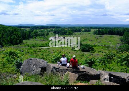 Zwei Touristen sitzen auf Little Round Top und schauen in Richtung Devil's Den im Gettysburg National Military Park Stockfoto