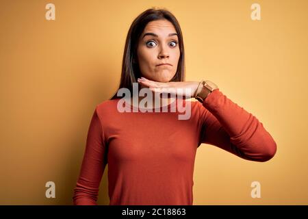 Junge schöne Brünette Frau trägt Casual T-Shirt über gelben Hintergrund Hals schneiden mit der Hand als Messer stehen, drohen Aggression mit furi Stockfoto