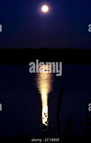 Kleine Fischerboot auf dem Fluss in der Nacht durch den Vollmond beleuchtet Stockfoto