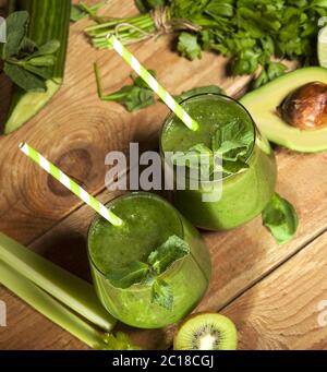 Frisch gemischter grüner Smoothie in Gläsern mit Trinkhalmen. Holzhintergrund. Stockfoto