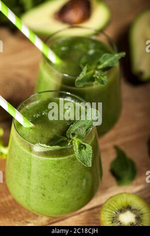 Frisch gemischter grüner Smoothie in Gläsern mit Trinkhalmen. Holzhintergrund. Stockfoto