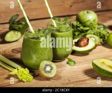 Frisch gemischter grüner Smoothie in Gläsern mit Trinkhalmen. Holzhintergrund. Stockfoto