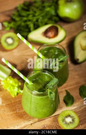 Frisch gemischter grüner Smoothie in Gläsern mit Trinkhalmen. Holzhintergrund. Stockfoto