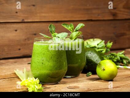 Frisch gemischter grüner Smoothie in Gläsern mit Trinkhalmen. Holzhintergrund. Stockfoto