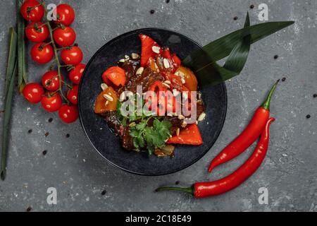 Rinderwak. Traditionelle chinesische mongolische Rindfleisch rühren braten in chinesischen Gusseisen Wok mit Kochstäbchen, Stein Schiefer Hintergrund. Draufsicht, Kopierbereich Stockfoto