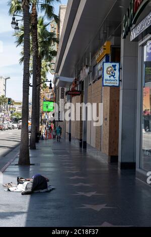 Hollywood, CA/USA - 8. Juni 2020: Eine obdachlose Frau schläft auf dem Hollywood Walk of Fame neben Unternehmen, die nach einer Reihe von Black Lives in die Läden gehen Stockfoto