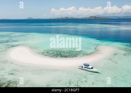 Luftaufnahme der Insel Taka Makassar im Komodo Nationalpark, Indonesien. Leeres Paradies kleine weiße Sandinsel auf Korallenriff. Luxusboot in Strandnähe. Stockfoto