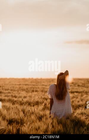 Junge schöne Mädchen genießen Natur auf dem Feld. Sonnenstrahlen. Schöne Teenage Model Mädchen in weißem Kleid läuft auf dem Feld, Sonne Licht. Leuchten Stockfoto