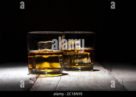 Zwei Gläser Whiskey mit Eiswürfeln auf weißen Holzplanken. Stockfoto