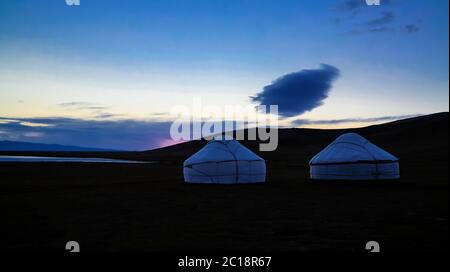 Wolke über den Jurten am Ufer des Song Kol Sees in der Morgendämmerung, Kirgisistan Stockfoto