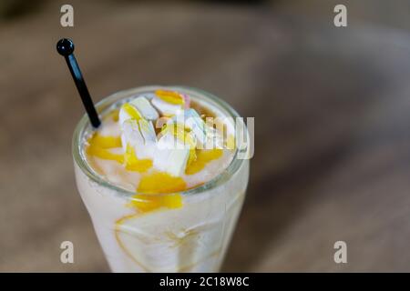 Mango Lassi oder Joghurt, indische beliebte Sommergetränk serviert in Glas, gekrönt mit Marshmallow. Stockfoto