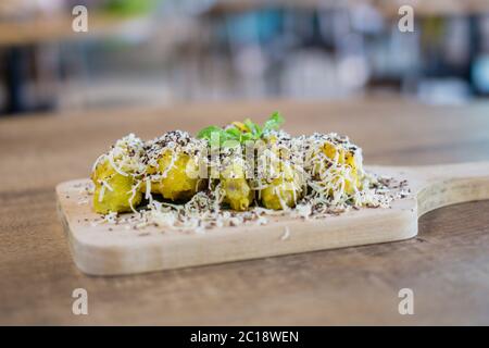 „Pisang Goreng Keju“ ist eine malaysische und indonesische Delikatesse, Bananenfritter mit viel Käse, geriebenen Pralinen und Kondensmilch. Stockfoto