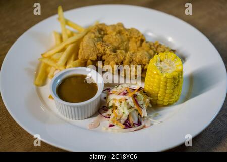 Frittiertes Hühnerfleisch mit Pommes Frites, Mais, Coleslaw dan Pilzsauce. Stockfoto