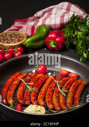 Wiener Würstchen in einer Pfanne auf schwarzem Hintergrund Stockfoto