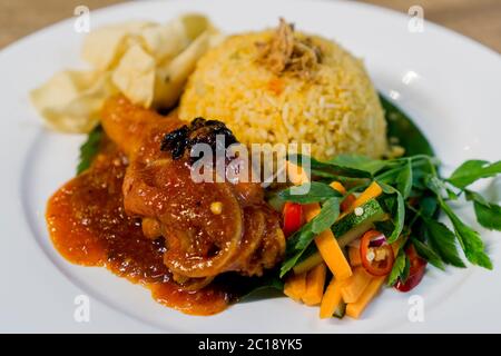 Traditioneller asiatischer Tomatenreis mit gebratenem Kunyit gebratenem Huhn masak merah serviert mit Soja-Cracker dan Gemüse. Stockfoto