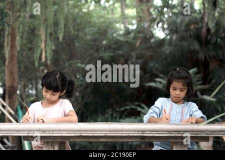 Zwei asiatische Mädchen Kinder sitzen und malen im Garten. Stockfoto